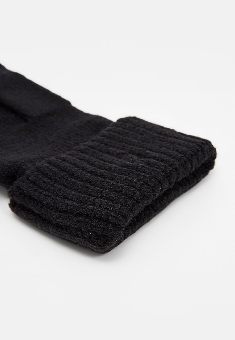 Czarny dziergany szalik z prążkowanym wzorem, z podwiniętym dołem. Wykonany z miękkiego materiału, wydaje się ciepły i gruby w strukturze.