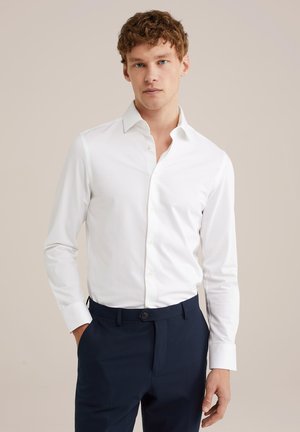 Witte, lange mouwen shirt van katoen, voorzien van een klassieke kraag en een knoopsluiting aan de voorkant. Draagt met marineblauwe broek, soepele textuur.