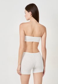 Top bandeau grigio in cotone e pantaloni coordinating, texture liscia, design aderente e cuciture ridotte al minimo. Vista posteriore che mostra uno stile semplice.