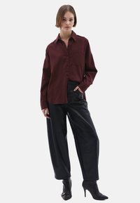 Camicia button-up bordeaux con tasca, abbinata a pantaloni neri alla moda e tacchi neri a punta. Tessuto morbido, vestibilità rilassata e design classico.