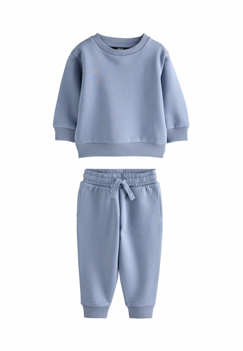 Lyseblå sweatshirt og joggingbukser i blødt materiale. Sweatshirten har en rund halsudskæring og ribbede manchetter; joggingbukserne har en elastisk talje.