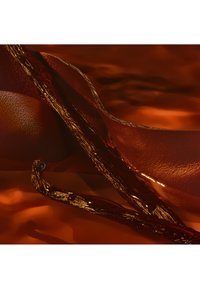 Kurvigt, texturerat rött läder sammanflätat med glänsande, mörkbruna komponenter; varm färgpalett med ljusa och djupa skuggor.