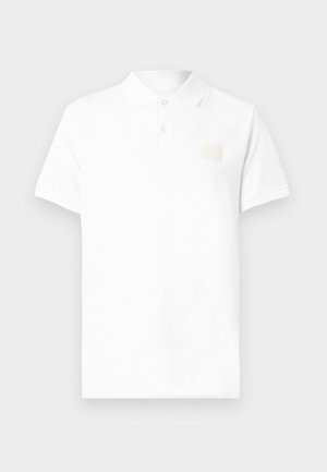 White polo shirt made of cotton, featuring a classic collar, short sleeves, and a small beige logo patch on the left chest area.