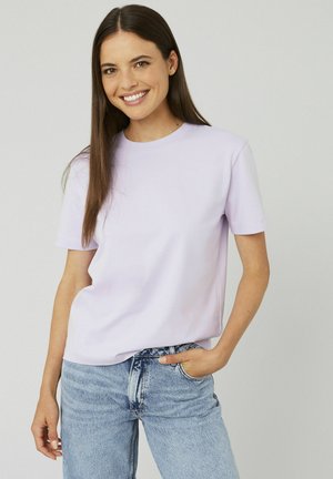 T-shirt lilas à manches courtes en tissu doux avec un col rond et une coupe décontractée, associé à un jean taille haute bleu clair.