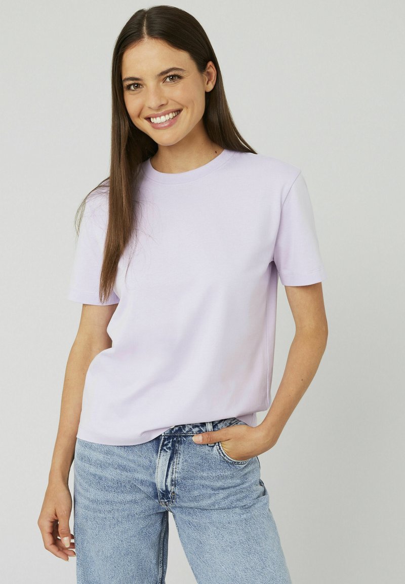 T-shirt lilas à manches courtes en tissu doux avec un col rond et une coupe décontractée, associé à un jean taille haute bleu clair.