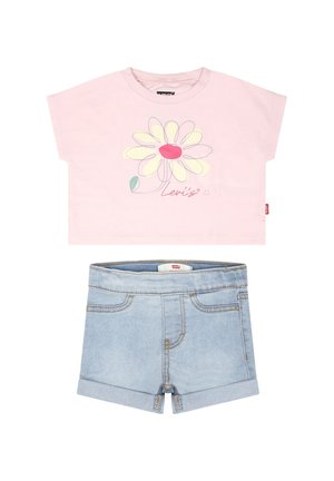 Camiseta de algodón rosa de manga corta con un diseño floral y el texto "Levi's", combinada con pantalones cortos de mezclilla azul claro con los dobladillos enrollados.