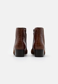 Botas tobilleras marrón con parte superior de cuero con relieve de cocodrilo, laterales de ante y tacón cuadrado. Cierre con cremallera en la parte posterior para una fácil colocación.