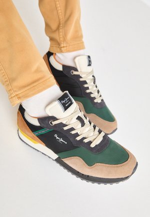 Zapatilla verde y negra con materiales de ante y malla, cordones crema, acentos multicolores y una suela texturizada. Logotipo de Pepe Jeans visible.