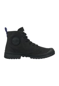 Botas de tobillo negras de ante, con suela de goma, puntera redonda, diseño de cordones y un parche de logo circular en el lado exterior.