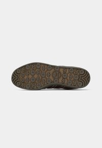 Schoenzool met een getextureerde, bruine rubberbasis met cirkelpatronen en het Adidas-logo. Ontworpen voor grip met een golvende rand.