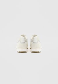 Hvite semskede sneakers med sølv detaljer. Har en teksturert hæl og polstret krage. Subtil merkevare på sålen. Minimalistisk design.