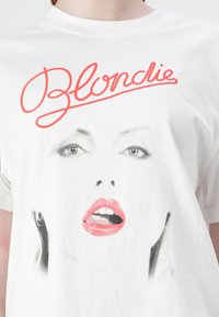 White cotton t-shirt featuring a graphic print of a woman's face, red lips, and the word "Blondie" in cursive red lettering above.