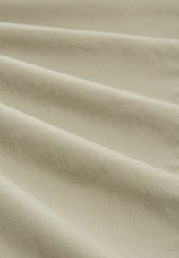 Material bej deschis cu o textură netedă, prezentând falduri moi și fluide și o strălucire subtilă. Ideal pentru tapițerie sau draperii.