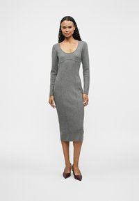 Grijze, getailleerde jurk met lange mouwen, ronde halslijn en naaddetails. Glad textuur, geribbelde stof, midi-lengte, gecombineerd met bordeaux paarse hakken.