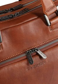 Borsa in pelle marrone con doppia cerniera e tirazip metallici, logo del brand impresso e dettagli di cucitura visibili su una superficie liscia.