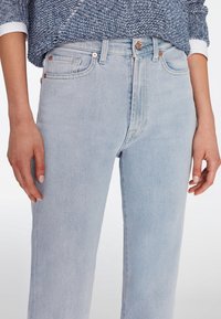 Světle modré džíny s vysokým pasem vyrobené z denimu, mají rovný střih, pět kapes a měděné kovové detaily.