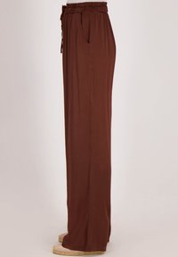Bruine, wijde broek gemaakt van zachte stof, met een elastische tailleband met trekkoord en zijzakken, soepele textuur en volledige lengte.
