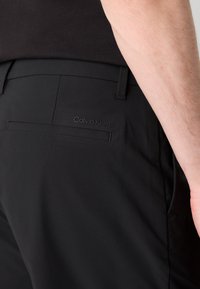 Sorte bukser med en glat tekstur og en tætsiddende pasform. Har en baglomme med diskret Calvin Klein branding.