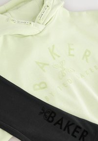 Svijetlozeleni dukserica s utisnutim tekstom i logom "BAKER by Ted Baker", u kombinaciji s crnom tkaninom koja sadrži crni tekst i logo "BAKER".