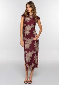 Vestido burdeos con silueta ajustada y mangas acampanadas. Presenta patrones florales dorados, tejido texturizado y una abertura lateral hasta la rodilla.