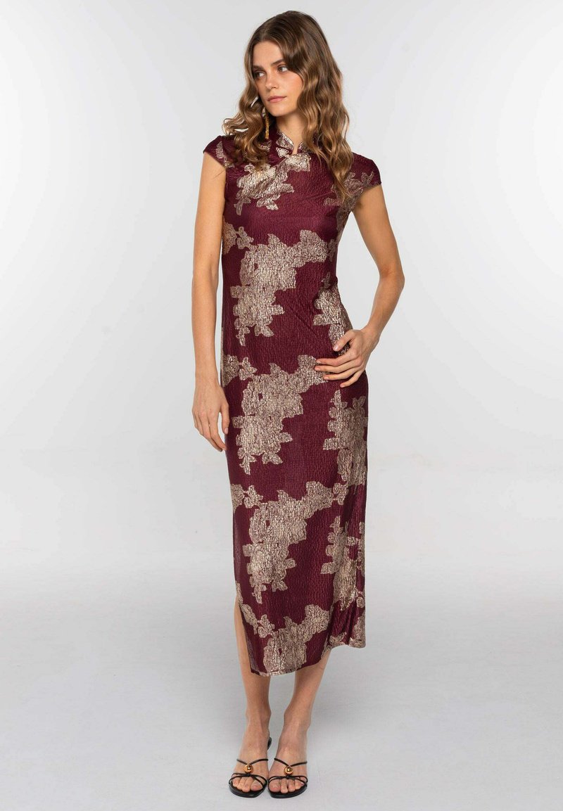 Vestido burdeos con silueta ajustada y mangas acampanadas. Presenta patrones florales dorados, tejido texturizado y una abertura lateral hasta la rodilla.