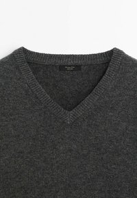 Pull en laine gris foncé à col en V, avec un col côtelé et une étiquette noire visible à l'intérieur de l'encolure.