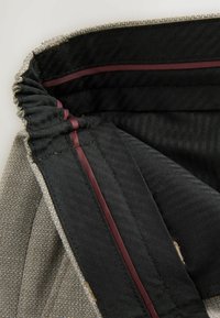 Gray woven fabric with black interior and maroon accents. Features a gathered edge and smooth texture, showcasing seams and lining details.