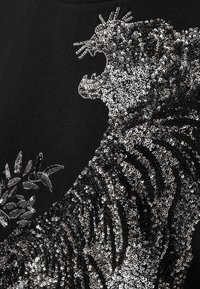 Μαύρο ύφασμα με σχέδιο τίγρης διακοσμημένο με παγέτες σε ασημί και μαύρο, με περίπλοκη λεπτομέρεια και λουλουδένιες πινελιές.