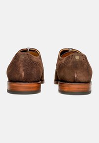 Braune Wildlederschuhe mit runder Form, die über Broguedetails, Lederinnensohlen und einen robusten Holzabsatz verfügen.