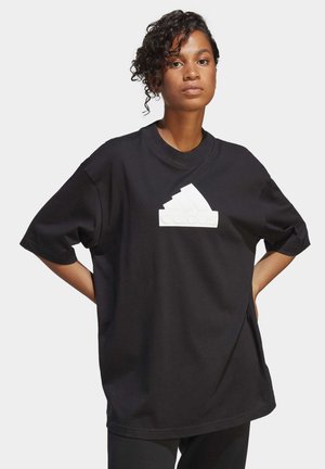 Camiseta negra oversize de algodón, con un logo en caucho blanco en un diseño triangular en el pecho, mangas cortas y cuello redondo.