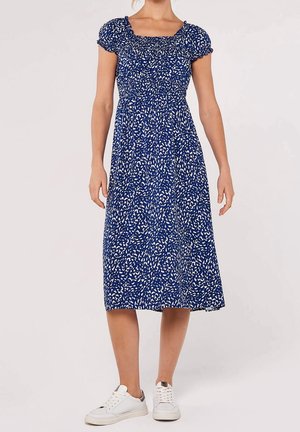 Vestito midi blu con motivi bianchi sparsi, corpetto arricciato e maniche corte a sbuffo, abbinato a sneakers bianche.