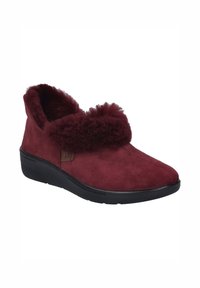 Bordeaux ruskindsko med en pelskant, flad sort sål og en enkel rektangulær logoetiket på siden; blød tekstur hele vejen igennem.