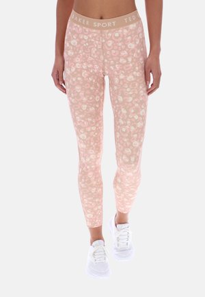 Różowe legginsy o dopasowanym kroju z delikatnym wzorem w panterkę, beżowa elastyczna talia z napisem "Ted Baker Sport", noszone z białymi trampkami.