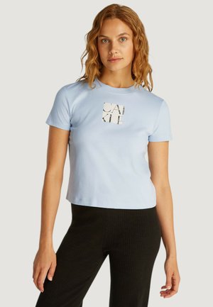 Maglietta a maniche corte blu chiaro realizzata in morbido cotone con un design corto. Presenta una stampa grafica in bianco e nero centrata sul petto.