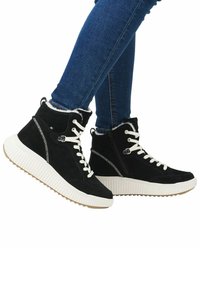 Bottines en suède noir avec des lacets blancs, une semelle épaisse blanche et des coutures décoratives. Équipées d'une fermeture éclair sur le côté pour un enfilage facile.