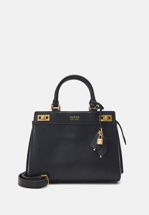 Zwarte leren Guess handtas met gouden hardware, bovenhandvatten, een afneembare schouderriem en een klein hangslot met sleutel detail.