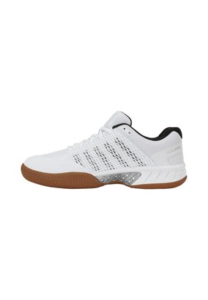 Chaussure de sport blanche basse avec semelle marron, doublure intérieure noire, tige en mesh et accent argenté près de la semelle intermédiaire.