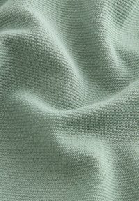 Tejido texturizado de color verde claro con un patrón acanalado, que exhibe suaves y lisas olas y pliegues delicados.