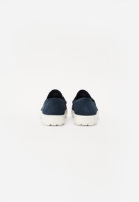 Marineblå semskede slip-on sko med en glat tekstur, hvide gummisåler og et lavprofil design. Ingen synlig hardware eller mønstre.