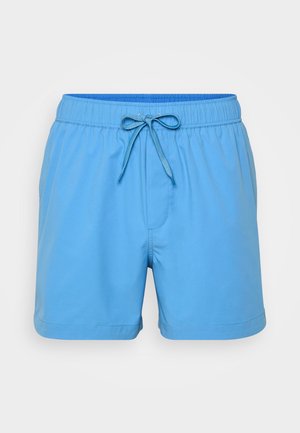 Modré plavky vyrobené z lehkého materiálu, s elastickým pasem a šňůrkou na stažení, a bočními kapsami. Hladká textura, délka po kolena.