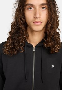 Felpa nera con zip realizzata in tessuto morbido, con zip argentata, logo piccolo sul lato sinistro del petto e cappuccio con stringa.