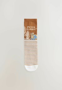 Chaussettes en coton marron avec un motif de Pierre Lapin, des rayures blanches et un bout blanc uni. Comprend le texte "PETER RABBIT" au-dessus de l'illustration.