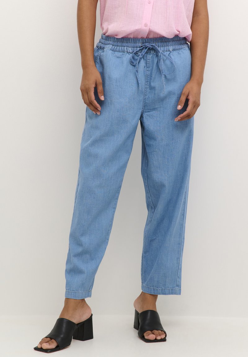 Ljusblå denimbyxor med lös passform, elastisk midja och dragsko. Kombineras med svarta klacksandaler.