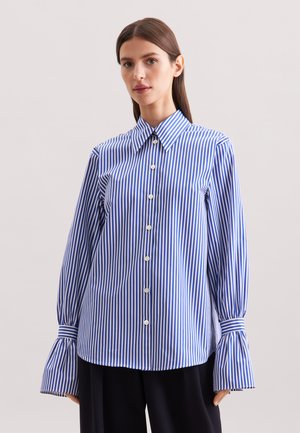 Chemise à col rayée bleue et blanche avec de longues manches évasées, dotée d'un front à boutons et d'une coupe décontractée. Texture lisse et tissée.