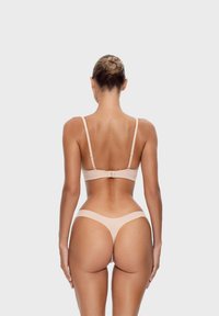 Set di lingerie nude chiaro composto da un bralette senza cuciture con spalline regolabili e un perizoma coordinato, entrambi realizzati in tessuto morbido ed elasticizzato.