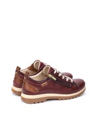 Scarpe in pelle marrone con finitura testurizzata, dotate di lacci bianchi, dettagli in metallo con cerniera e suola resistente per una buona aderenza.