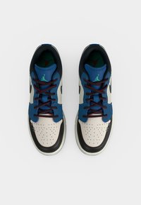 Ζευγάρι χαμηλά sneakers με μπλε, λευκά και μαύρα χρωματικά μπλοκ, κόκκινα και μαύρα κορδόνια και γαλαζοπράσινα λογότυπα Jumpman στις γλώσσες.