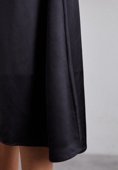 Svart satin kjole med en jevn tekstur, kne-lengde og en subtil glans. Har en ren, rett kant og elegant fall.