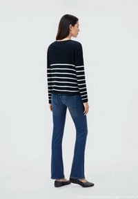 Pulover z mornarskimi črtami in belimi črtami, dolgimi rokavi, ohlapen kroj. V kombinaciji z modrimi širokimi jean hlačami in črnimi balerinkami. Minimalističen dizajn.