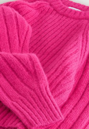 Kirkas roosa sviiter, mis on valmistatud kergelt karvast, ribakujulistest materjalidest. Omab laia kaelust ja pikkade varrukate tekstuurseid detaile.